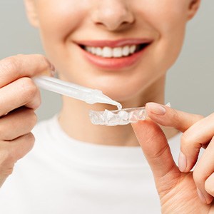 Woman placing whitening formula in dental tray