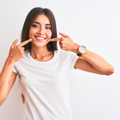 Happy woman in white t-shirt pointing at her teeth