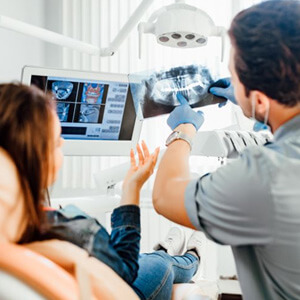 Dental team members showing X-ray to patient