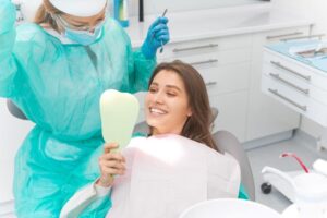 Happy dental patient looking at her teeth in mirror